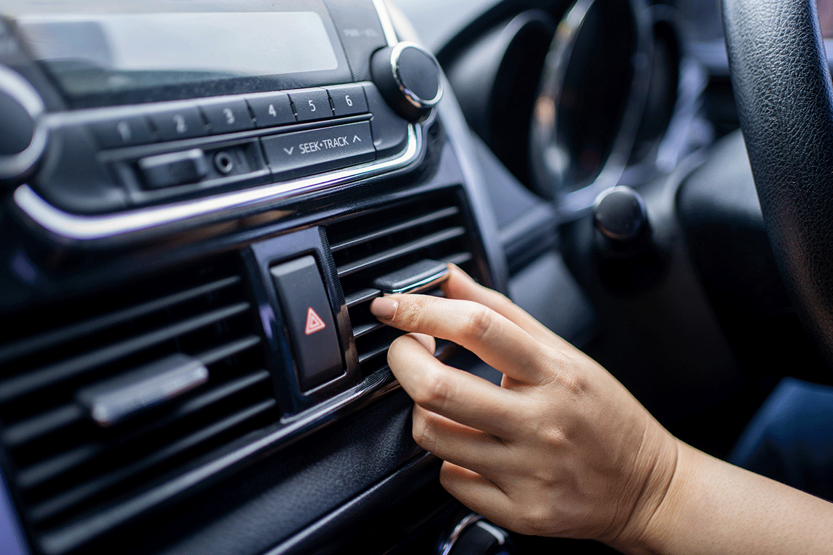 Eine Hand richtet die Klima in einem Auto.