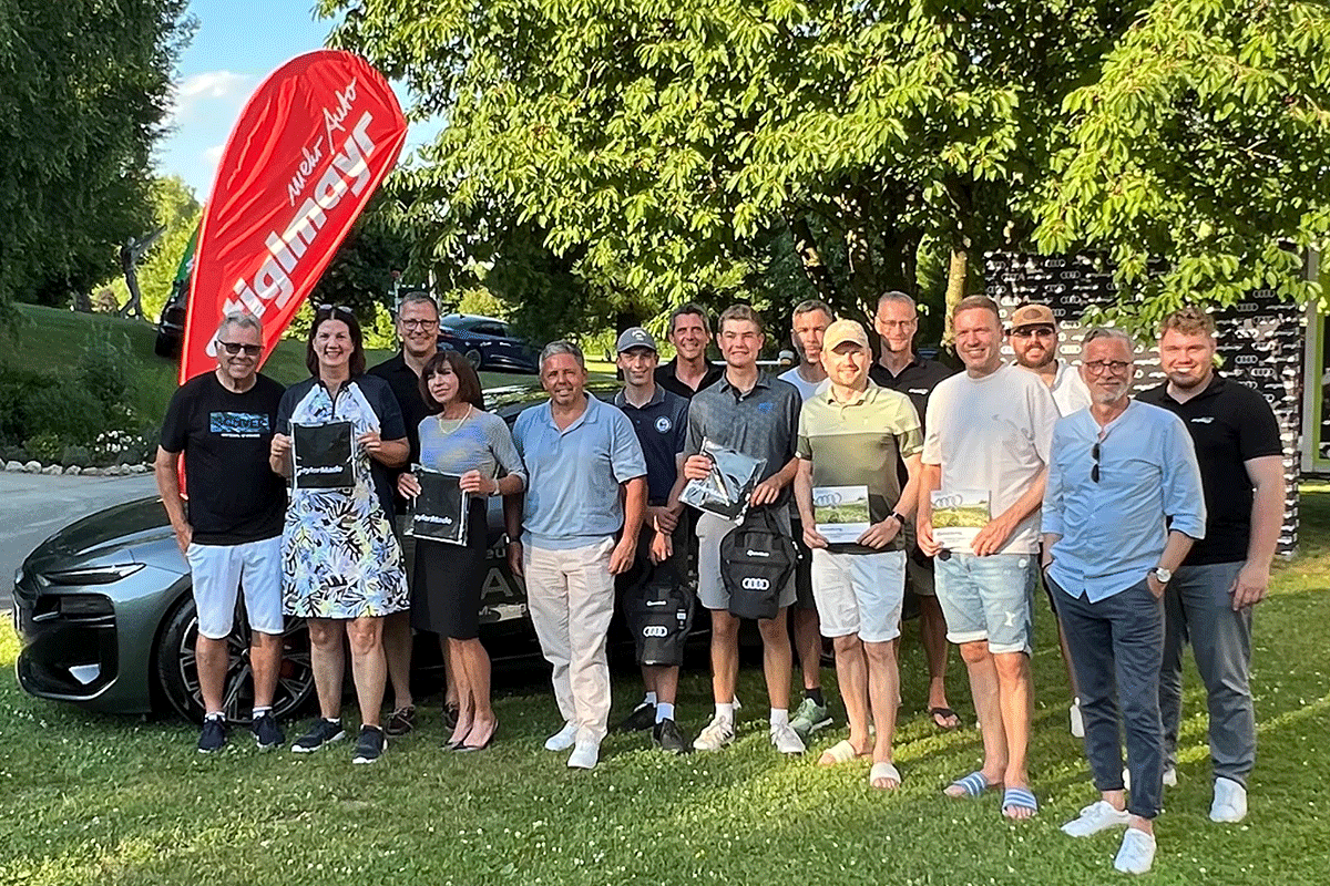 Teilnehmer des Audi quattro cup vor einem Auto unseres Autohauses und rotem Beachflag
