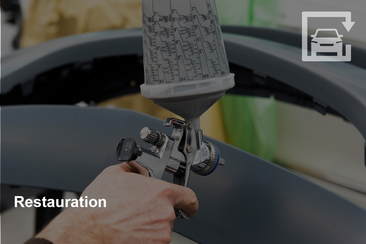 Lackierpistole mit Autoteil im Hintergrund