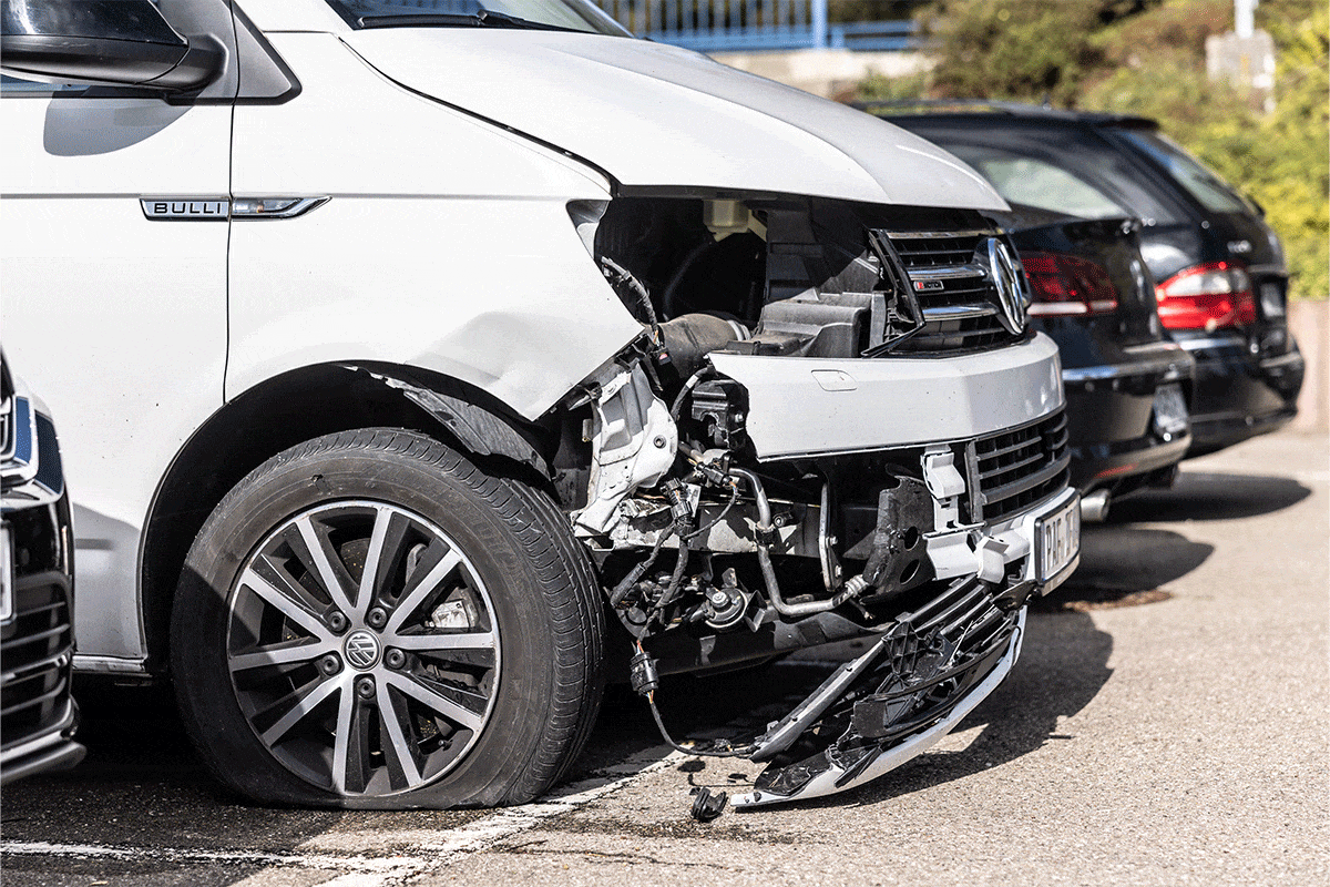 Ein weißes Auto mit kaputter Front steht neben anderen Autos.