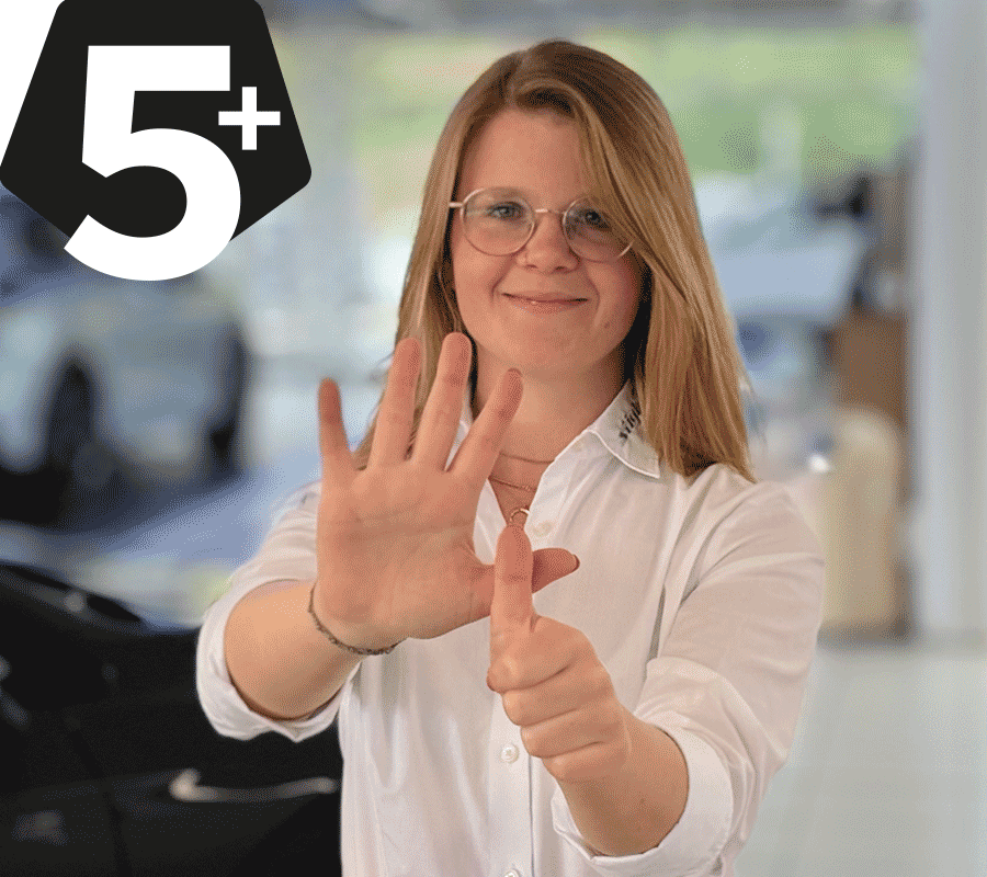 Mitarbeiterin zeigt mit ihrer Hand ein 5+ Zeichen
