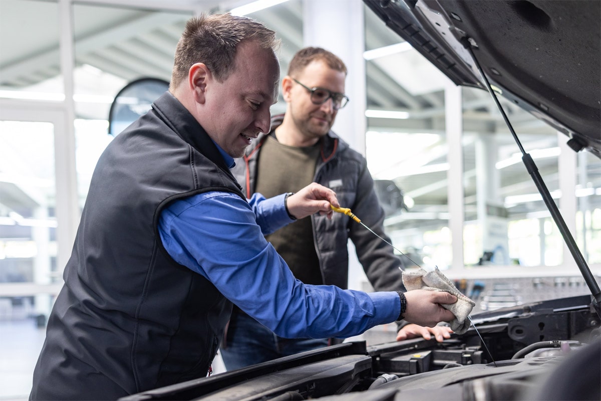 Serviceberater prüft gemeinsam mit dem Kunden den Ölstand.